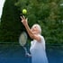 Elderly woman playing tennis, throwing ball up