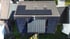 Dach eines Hauses mit Solarmodulen, Schornstein und zwei Dachfenstern, umgeben von weiteren Dächern und Bäumen.