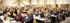 Publikum klatscht bei einer Konferenz in einem hellen Saal mit Holzelementen.