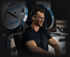 Ein lächelnder Mann mit Brille trainiert an einer Kraftstation mit Gymleco-Hantelscheiben im Fitnessstudio.