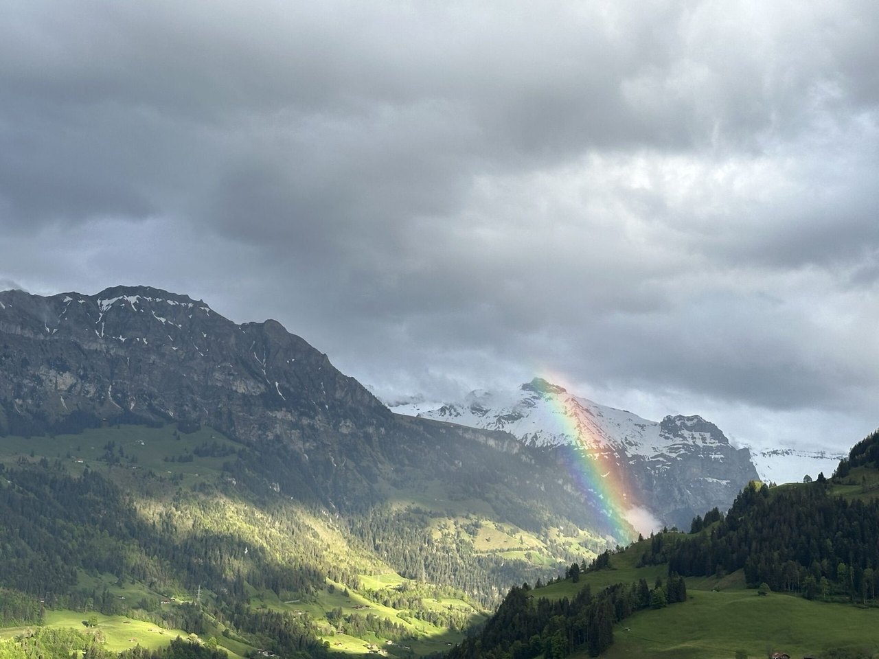Regenbogen über einem grünen Bergtal