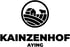Logo: Schwarzes rundes Symbol mit Bauernhof und Kuh auf Hügeln, darunter der Text "KAINZENHOF AYING".