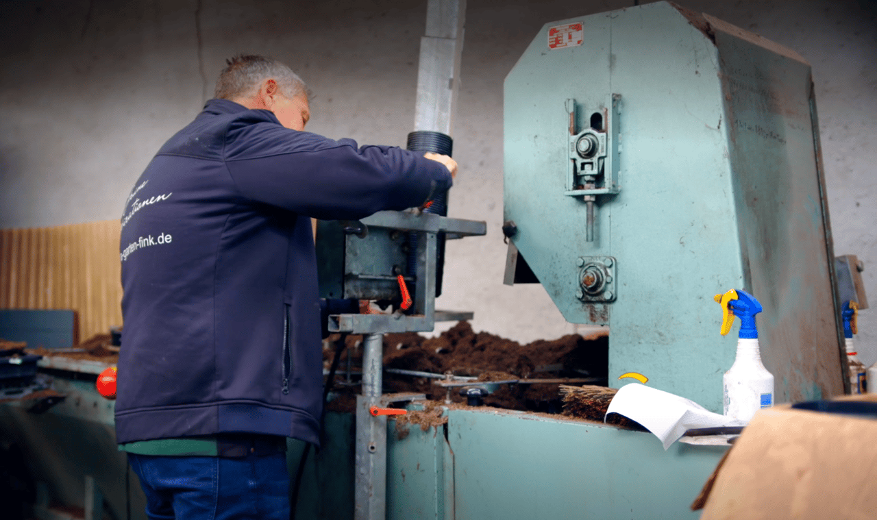 Mitarbeiter arbeitet an der Topfmaschine in der Gärtnerei