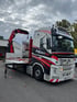 Weißer Volvo LKW von Heavycont mit rotem Ladekran hebt eine verpackte Last auf die Ladefläche.