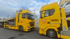 Zwei gelbe ADAC-LKW von Hess stehen auf einer Straße unter bewölktem Himmel.