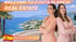 Two women in blazers on a balcony overlooking the Costa Blanca coast. Text: "WELCOME TO COSTA BLANCA! REAL ESTATE Karolina & Jannine"