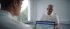 Zwei Männer in weißer Arbeitskleidung sitzen sich in einem hellen Büro an einem Tisch mit Laptop gegenüber.
