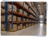 Hohe Palettenregale mit Kartons in einem modernen Logistikzentrum mit breiten Gängen.