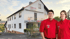 Zwei Personen in roten Hemden stehen vor einem weißen Gebäude mit dem Heyer-Logo.