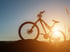 Mountainbike-Silhouette bei Sonnenuntergang auf einem Hügel mit hohem Gras.