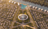 Aerial view of a circular plaza with a logo, surrounded by residential areas and a river with buildings.