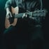 Hands on guitar strings in dark production studio