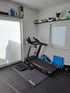 Heim-Fitnessraum mit Laufband F31, Tacx-Matte, Balance Board, Hanteln und Fitnessgeräten.