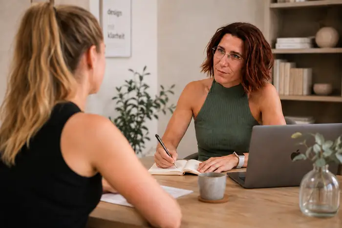 Lydia Grapentin im Gespräch mit einer Klientin am Tisch, Notizbuch und Laptop