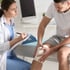 A doctor examines a patient's bandaged knee.
