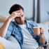 Man on couch holding head, seeking headache relief
