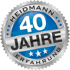 Silbernes Abzeichen mit blauer Mitte, Aufschrift "HEIDMANN 40 JAHRE ERFAHRUNG" und Sternen.