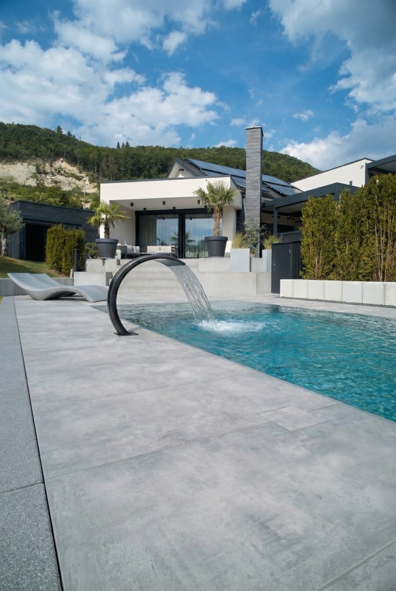 Moderner Pool mit Wasserfall-Element und grauem Rand