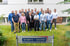 Das Team der Schmitz + Sachse Ingenieurgesellschaft mbH posiert lächelnd auf einer Rasenfläche vor dem Firmengebäude.