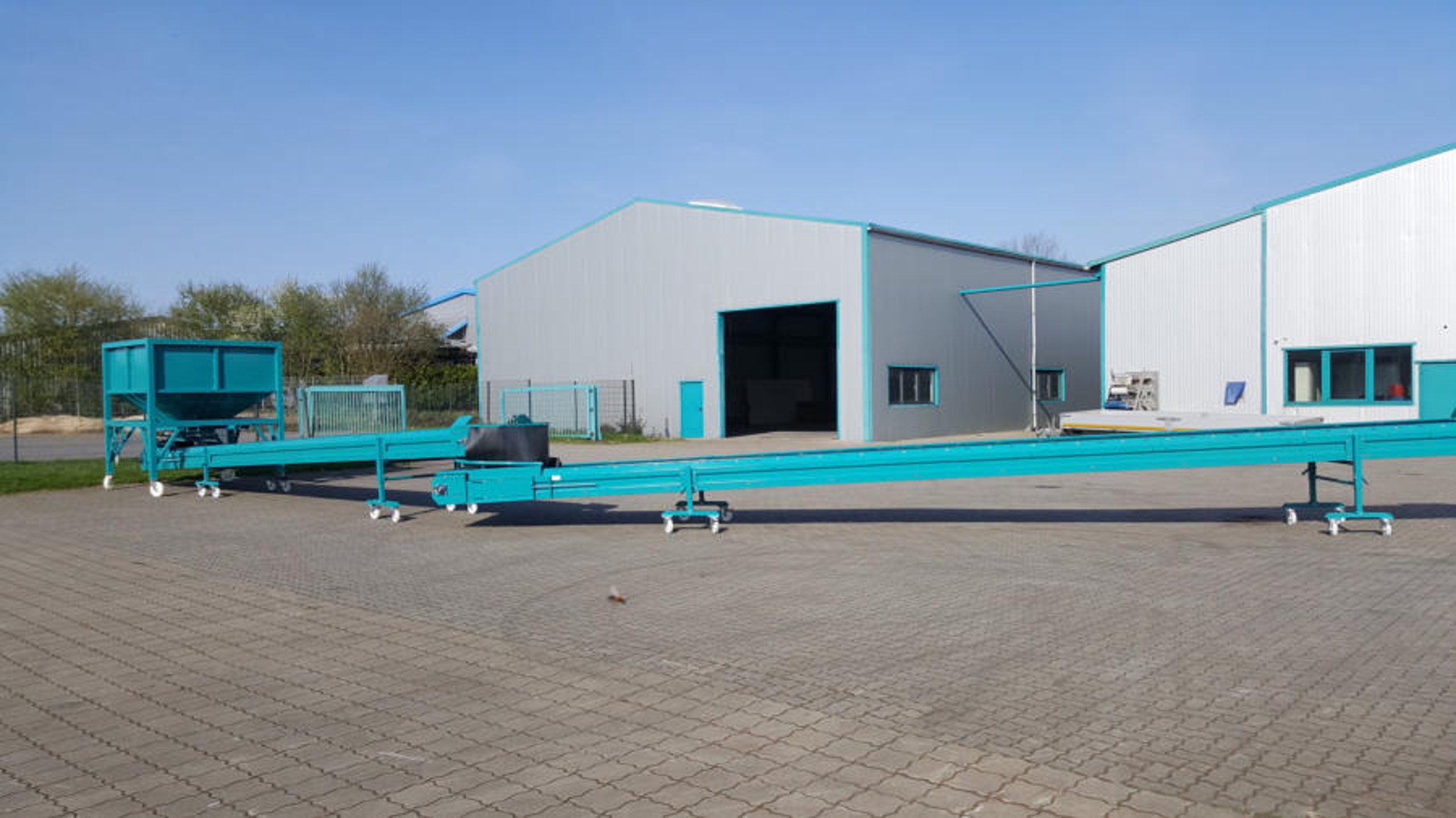 Turquoise conveyor system in front of warehouses