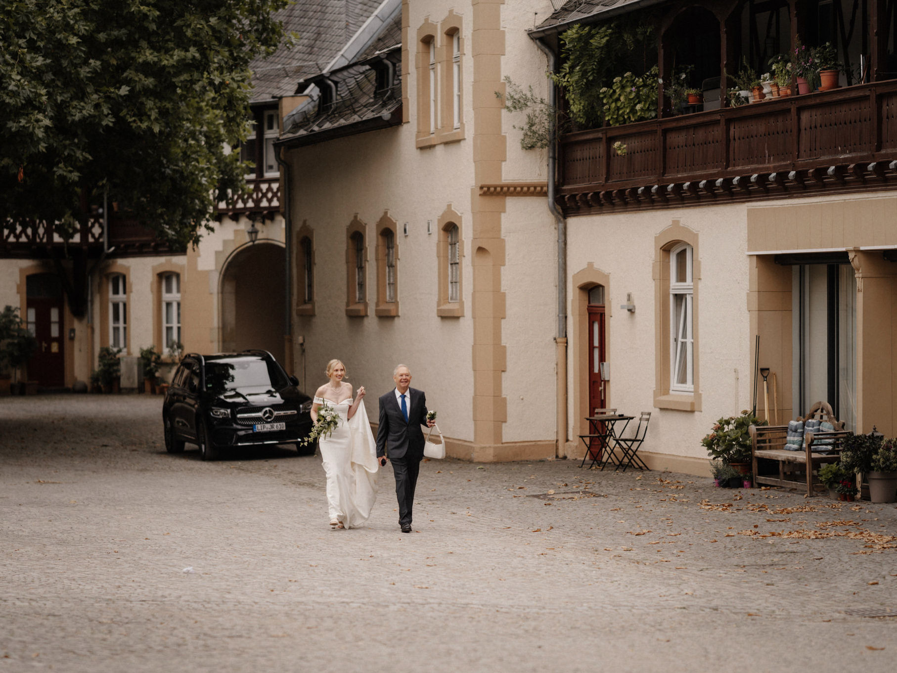 Braut kommt mit ihrem Vater über den Innenhof von Schloss Eller in Düsseldorf.
