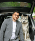 Mann mit Brille und Husky sitzen im Kofferraum eines Autos.