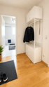 Flur mit Laminatboden, weißer Garderobe samt Kommode und Blick in ein hell gefliestes Badezimmer mit Badewanne.