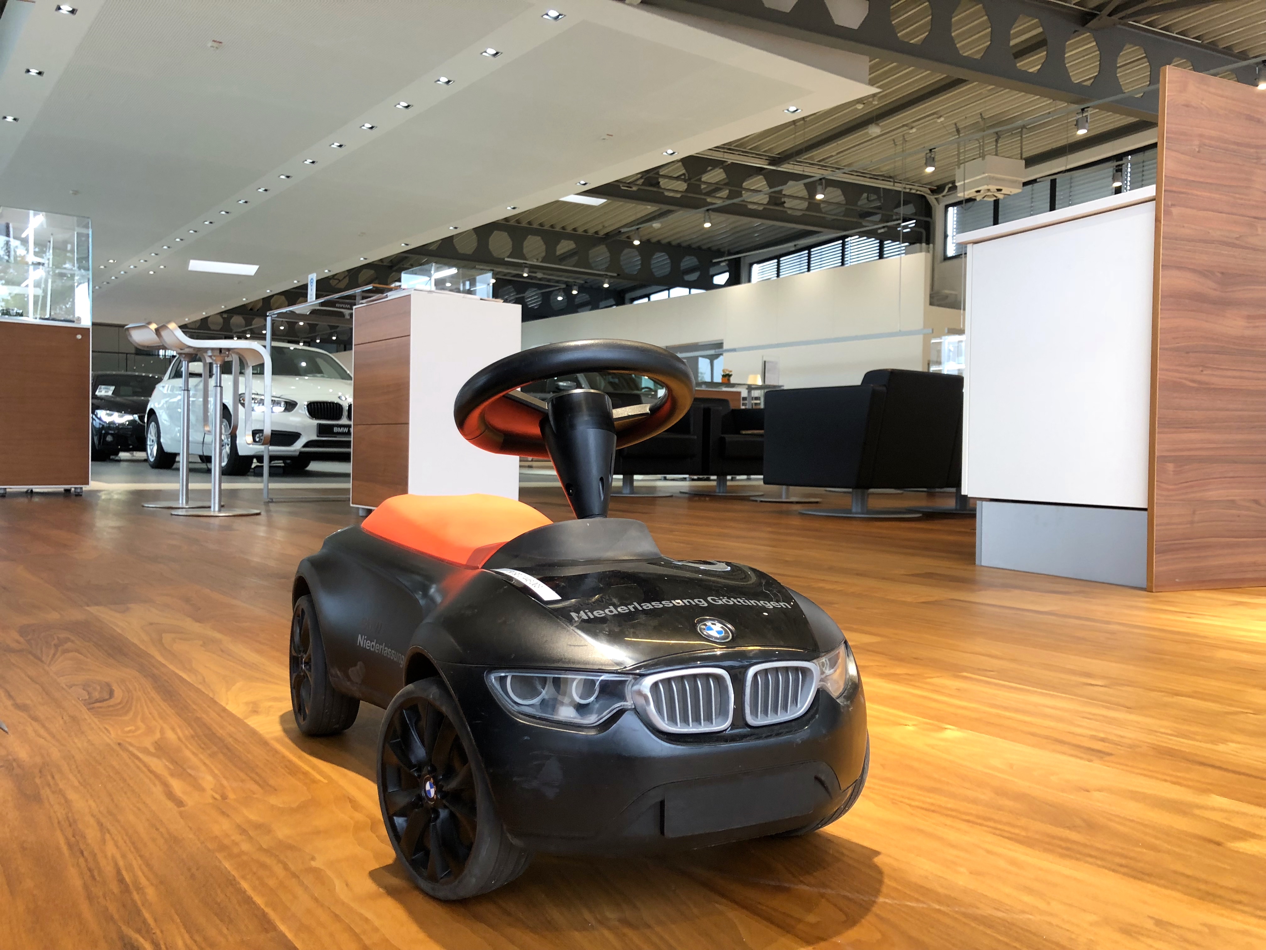 BMW Niederlassung Göttingen – Kinderfahrzeug auf Holzboden im Ausstellungsbereich