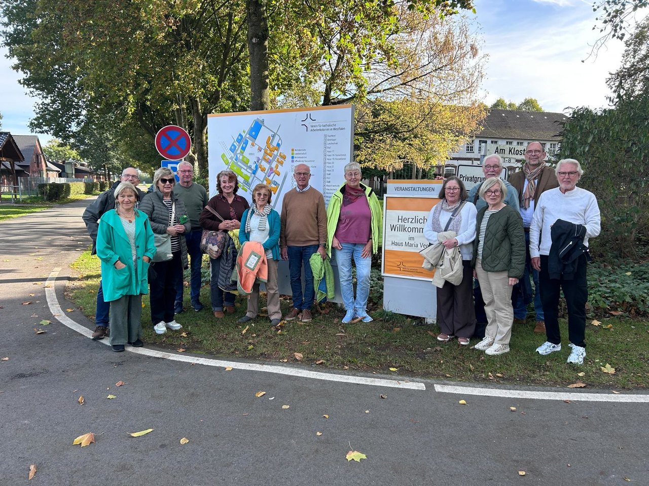 Gruppe der Beraterteams vor dem Lageplan und dem Willkommensschild von Haus Maria Veen