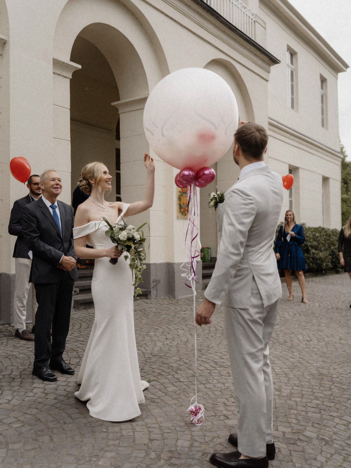 Braut hält einen großen Luftballon im Innenhof von Schloss Eller in Düsseldorf.