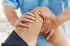 A chiropractor or physical therapist treating a patient's knee.