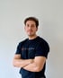 Mann in schwarzem T-Shirt mit Aufschrift "Das ElektroWerk" und gekreuzten Armen.