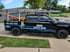 Black Family Garage Door Service wrapped truck with ladders on top, parked on a street curb. Text: "402-628-7695"