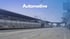 Eine Geschäftsfrau im dunkelblauen Anzug sitzt an einem Tisch und schaut nach links.