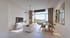 Modern living room at sunset with city view, large windows, L-shaped sofa, and fireplace.