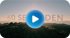 Sonniger Sonnenaufgang über den Bergen mit einem blauen Play-Button und dem Text "60 SEKUNDEN".
