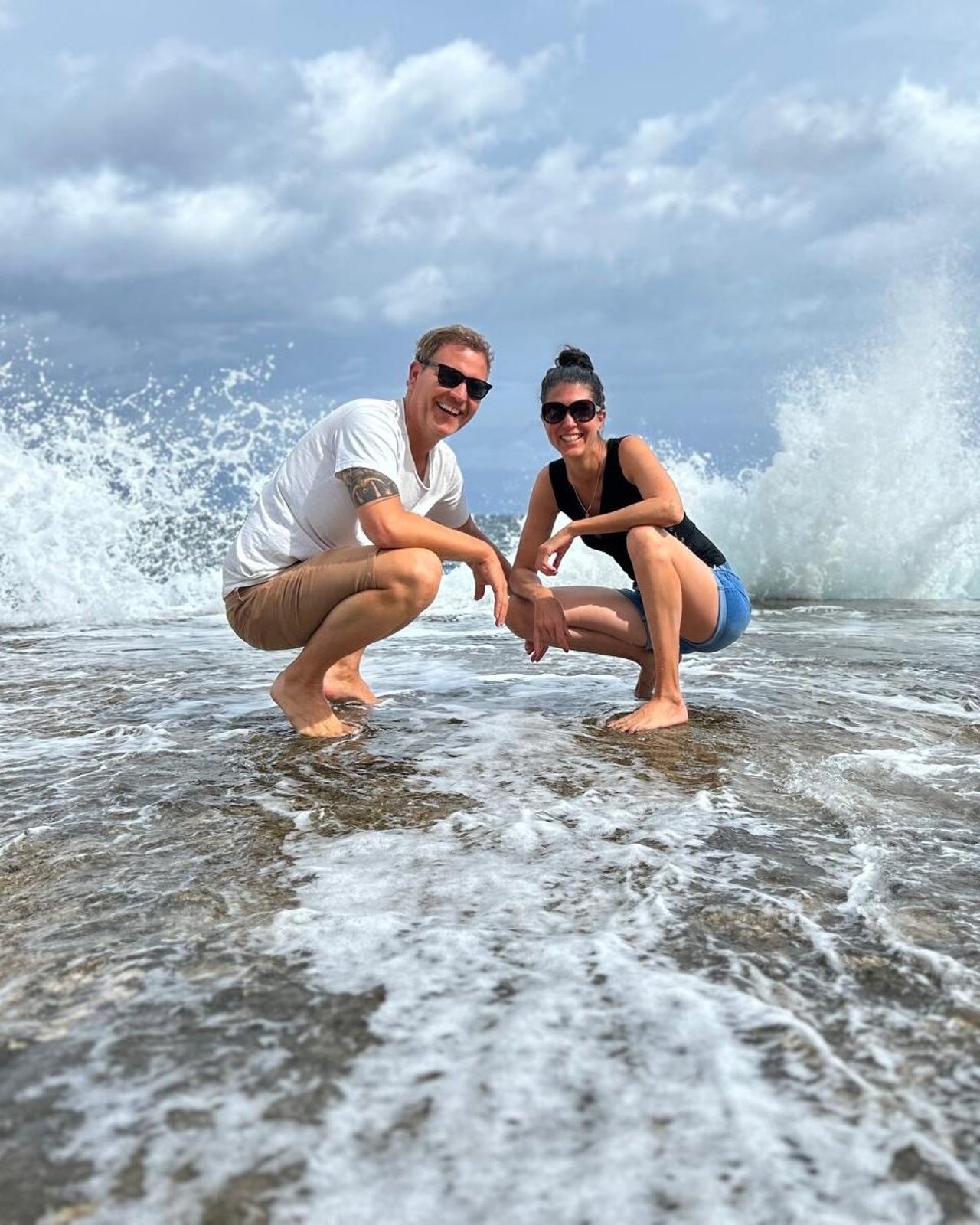 Seraina und Reto lachend in der Brandung am Meer