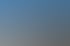 Eine lachende, ältere Frau mit erhobenen Armen schaukelt im Freien vor blauem Himmel.