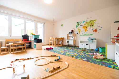 Spielzimmer mit Holzeisenbahn, Strassenteppich und Weltkarte.