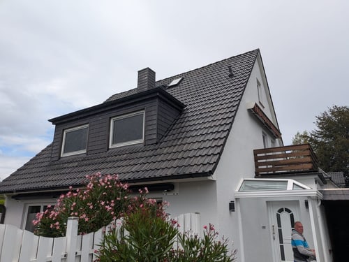 Haus mit rot beschichtetem Dach und Photovoltaik-Anlage