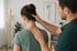 Osteopath untersucht die Halswirbelsäule und Nackenmuskulatur einer Patientin in einer osteopathischen Praxis.