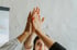 Drei Hände von zwei Personen geben sich ein High-Five, wobei eine Person unten in der Mitte lächelt.