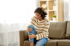 Woman experiencing knee arthritis pain sitting on sofa