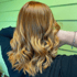 Rückenansicht einer Person mit glänzendem, gewelltem, kupferfarbenem Haar mit blonden Highlights.
