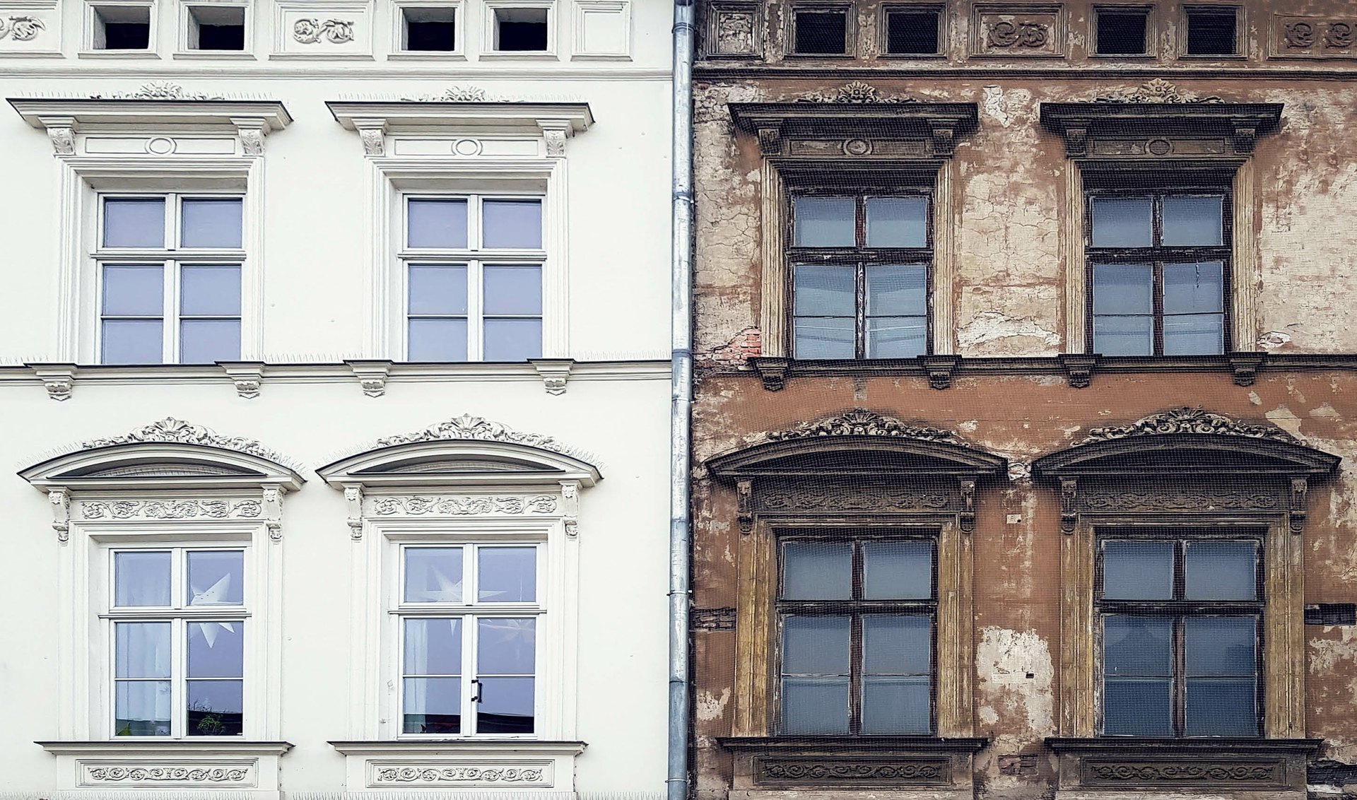 Altbaufassade: links saniert und hell gestrichen, rechts mit abgeplatztem Putz