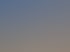 Rohbau eines Einfamilienhauses aus roten Ziegeln mit fertigem Dachstuhl unter blauem Wolkenhimmel.