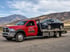 Towing Sandy flatbed towing service transporting a sedan on a red rollback tow truck through a mountain roadway in Sandy, UT