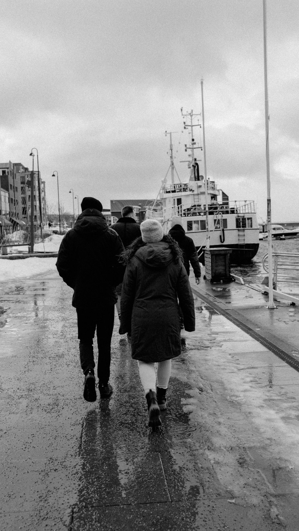 Zwei Personen gehen im Regen am Hafen entlang, Schwarz-Weiß