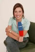 Smiling woman with brown hair sitting on a green chair, holding a blue and red microphone with "D:SF" logo.