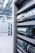 Elektrischer Schaltschrank mit vielen Sicherungen und farbigen Kabeln in einem Industrieraum.